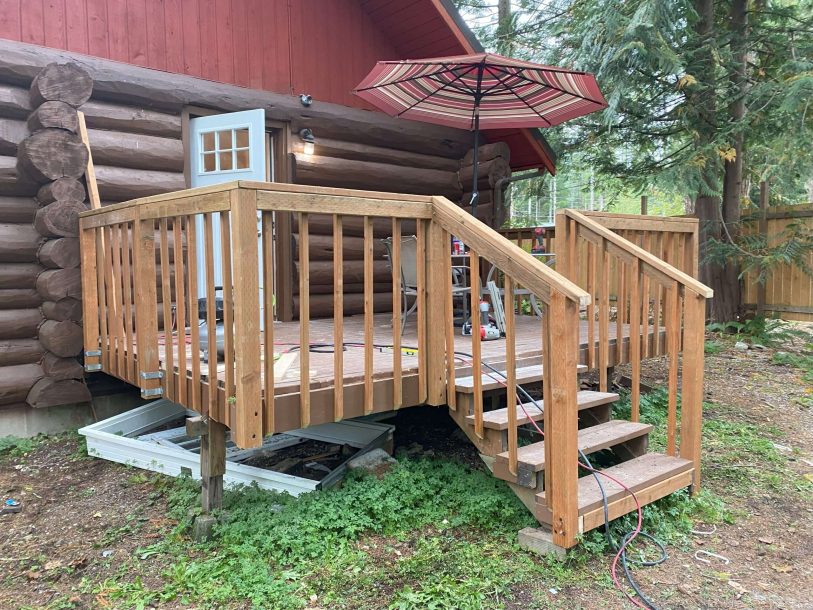 A wooden deck extends the livable space of a classic log cabin.