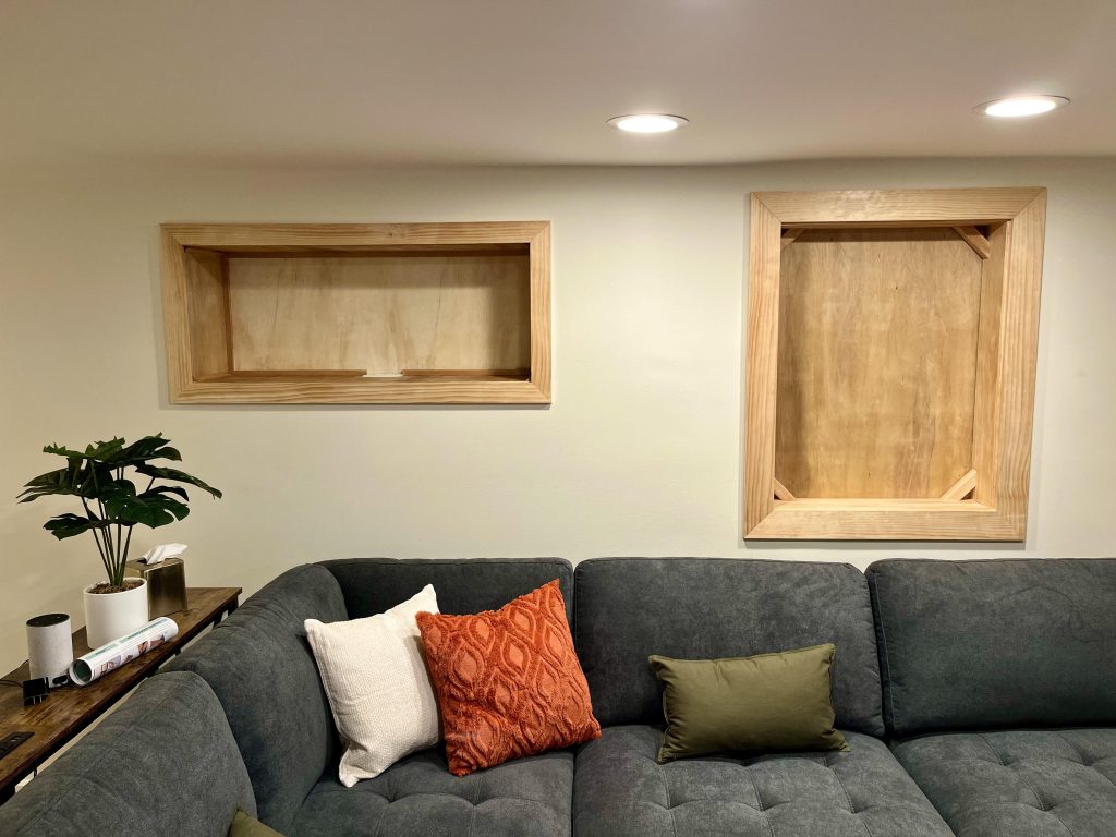 Custom built-in shelving covers undersirable cut outs while adding additional storage in this basement conversion.