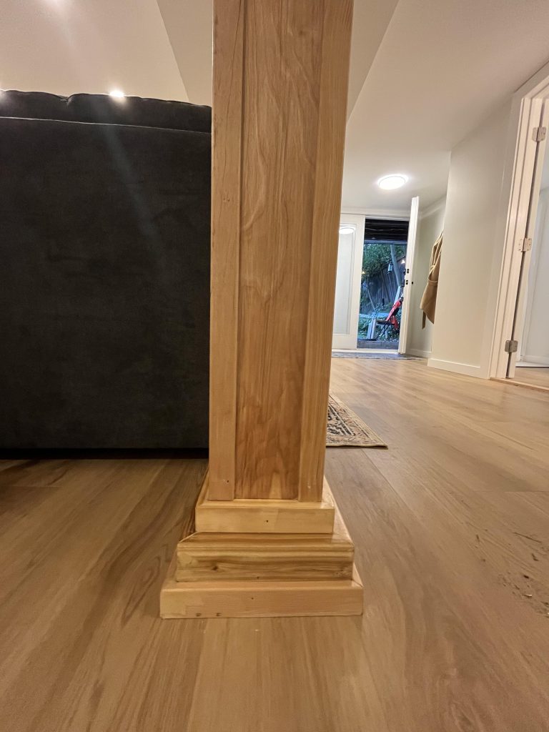 Decorative wood paneling covers the structural central pillar of this basement to ADU conversion.