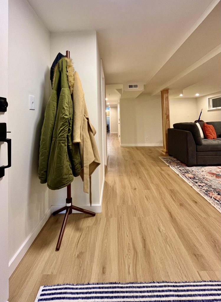 A coat rack sits at the entrance of a finished basement living room.