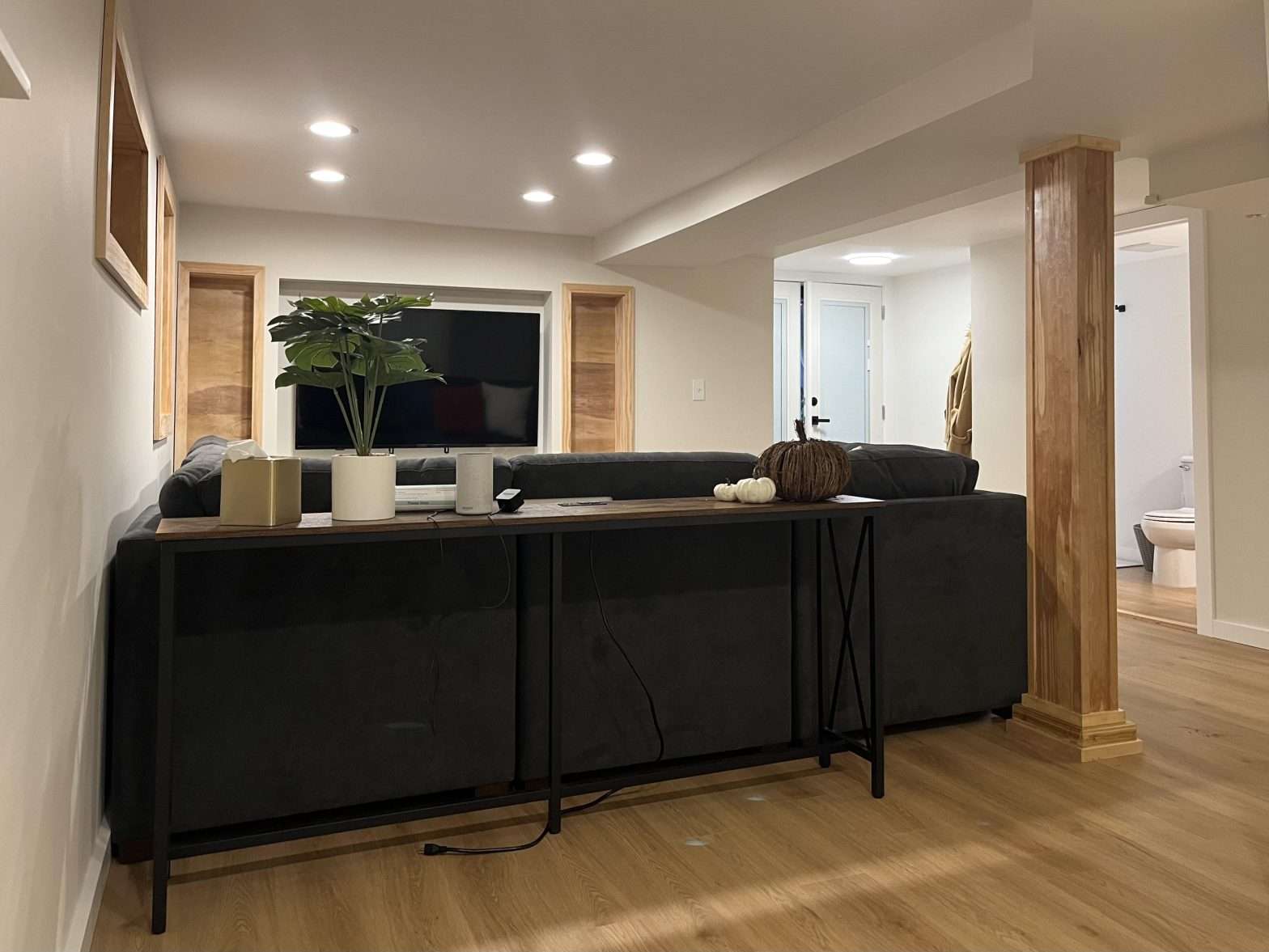 A finished basement with recessed lighting, wood-look LVP floors, and built-in storage nooks.