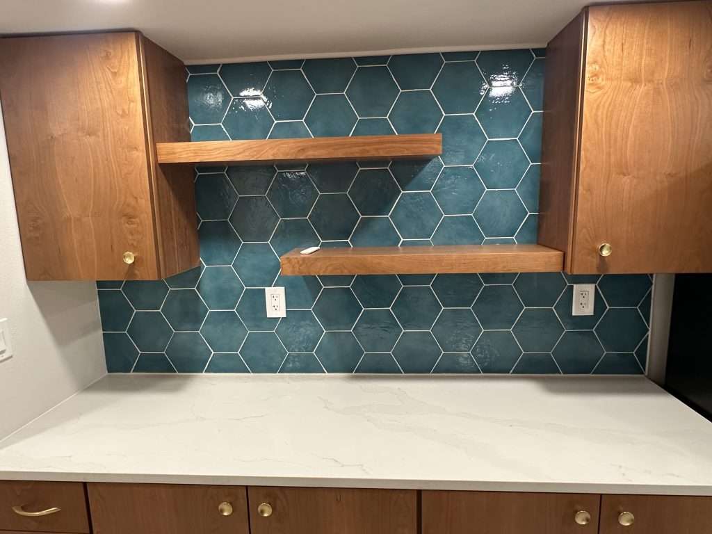 Modern kitchen with teal hexagon tiles and flat, minimalist cabinets.