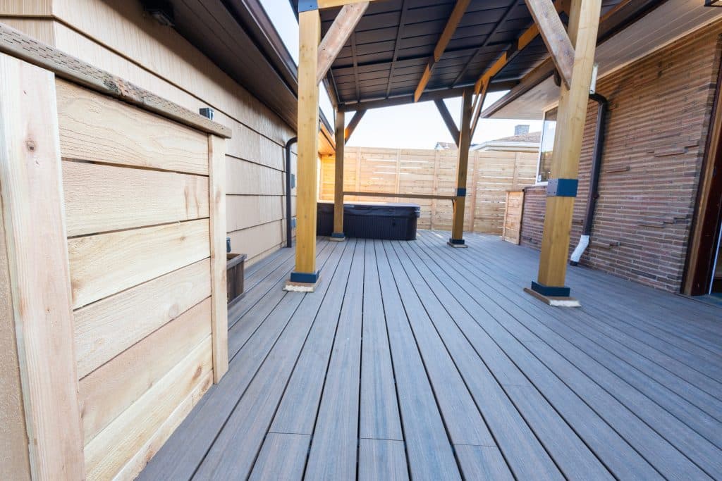 A wood deck with a roof and privacy fence for the hot tub.