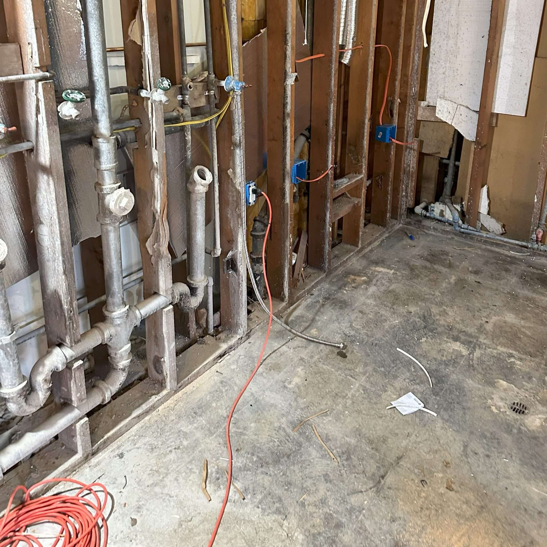 A corner of the laundry room remodel shows the plumbing within the opened walls.