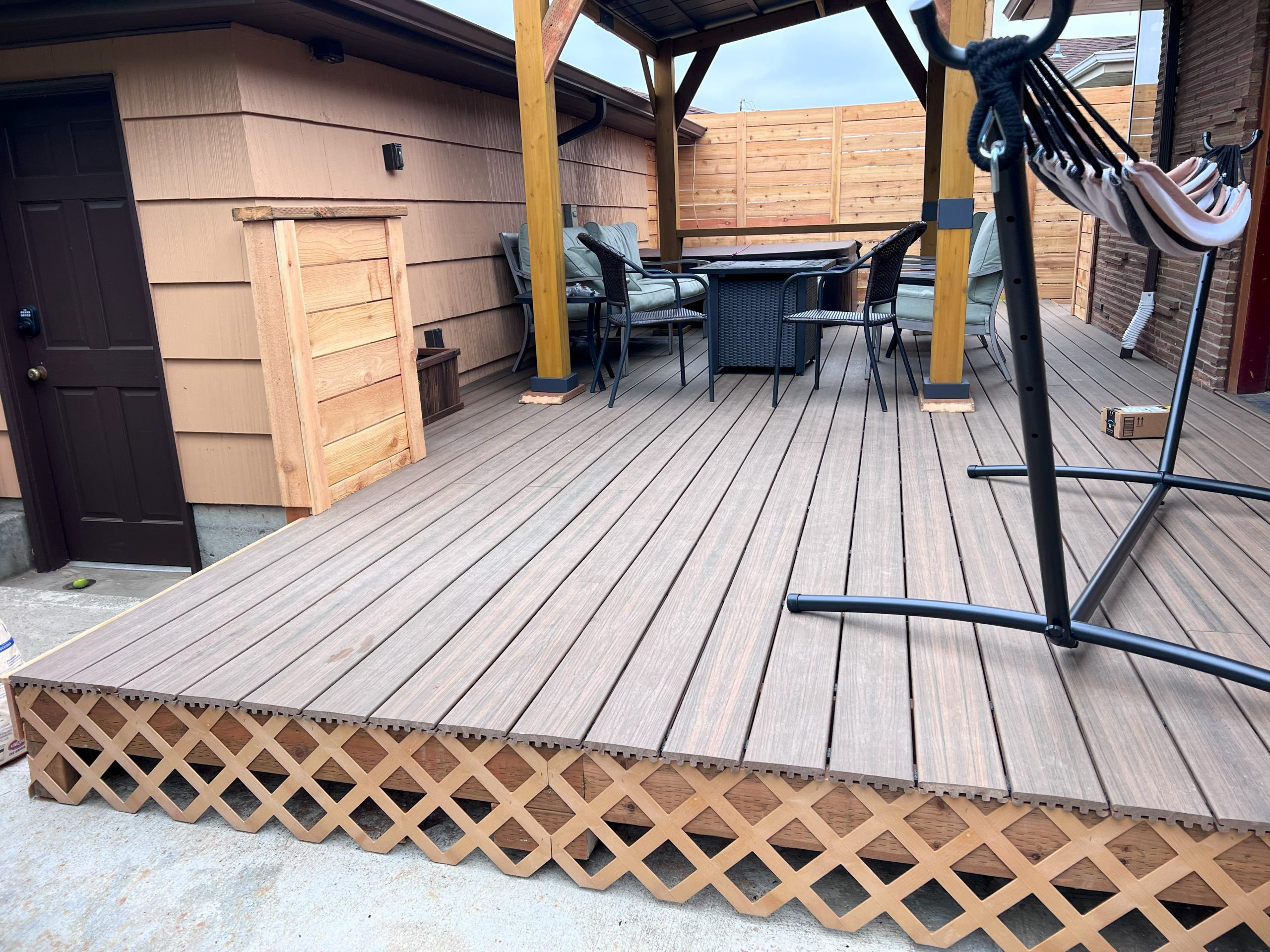 A lattice border adorns the bottom edge of a furnished wood deck.