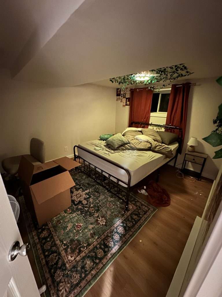 Bedroom one of two in a finished basement conversion is features laminate floors, a recessed window, and recessed overhead lighting.