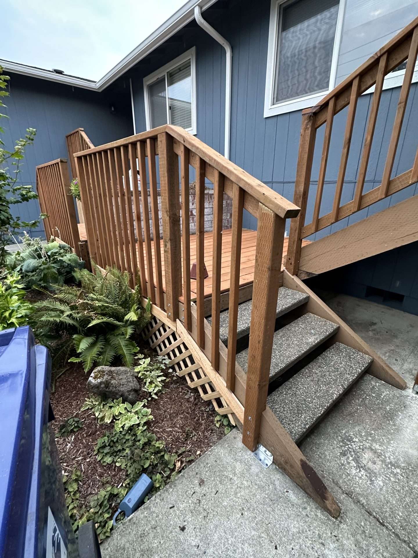 A rebuilt cedar deck with wood railings, stone steps, and a lattice deck skirt. 