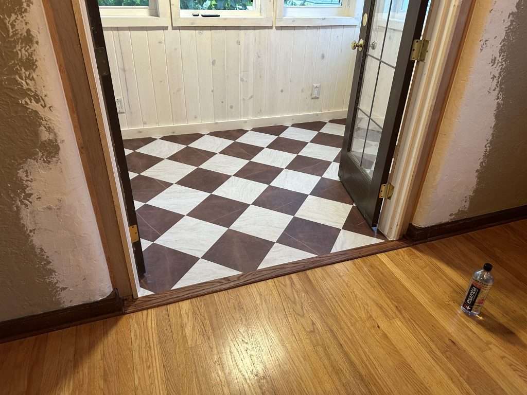 the entryway to a sunroom extension that features glass french doors, checkerboard floors, and a row of windows to let in natural light.
