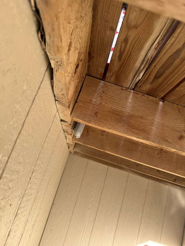 The underside of a deck with damaged joists and water logged deck boards.