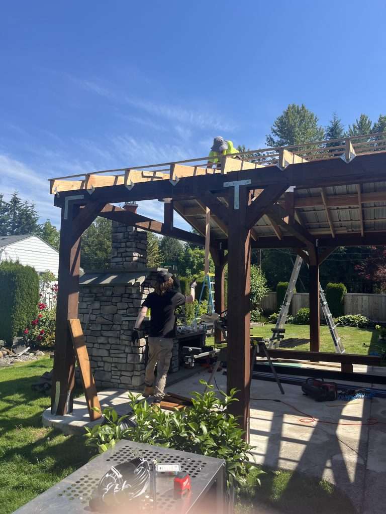 Two workers assembling a custom patio cover. 