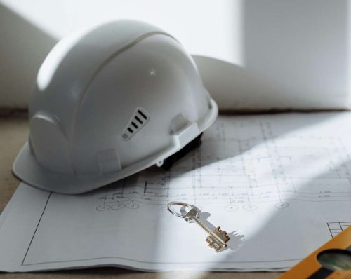 A key and hard hat lay on a floorplan.