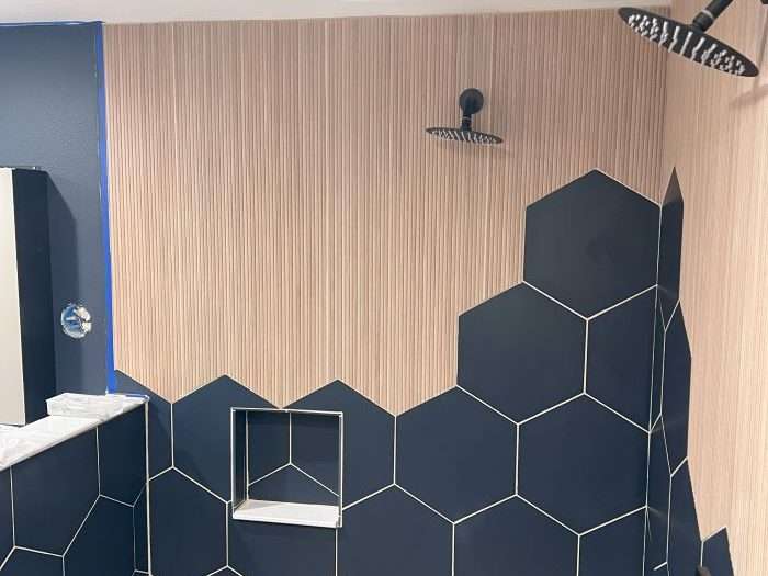 A contemporary walk-in shower with custom tile work, three separate shower heads, and built-in storage.
