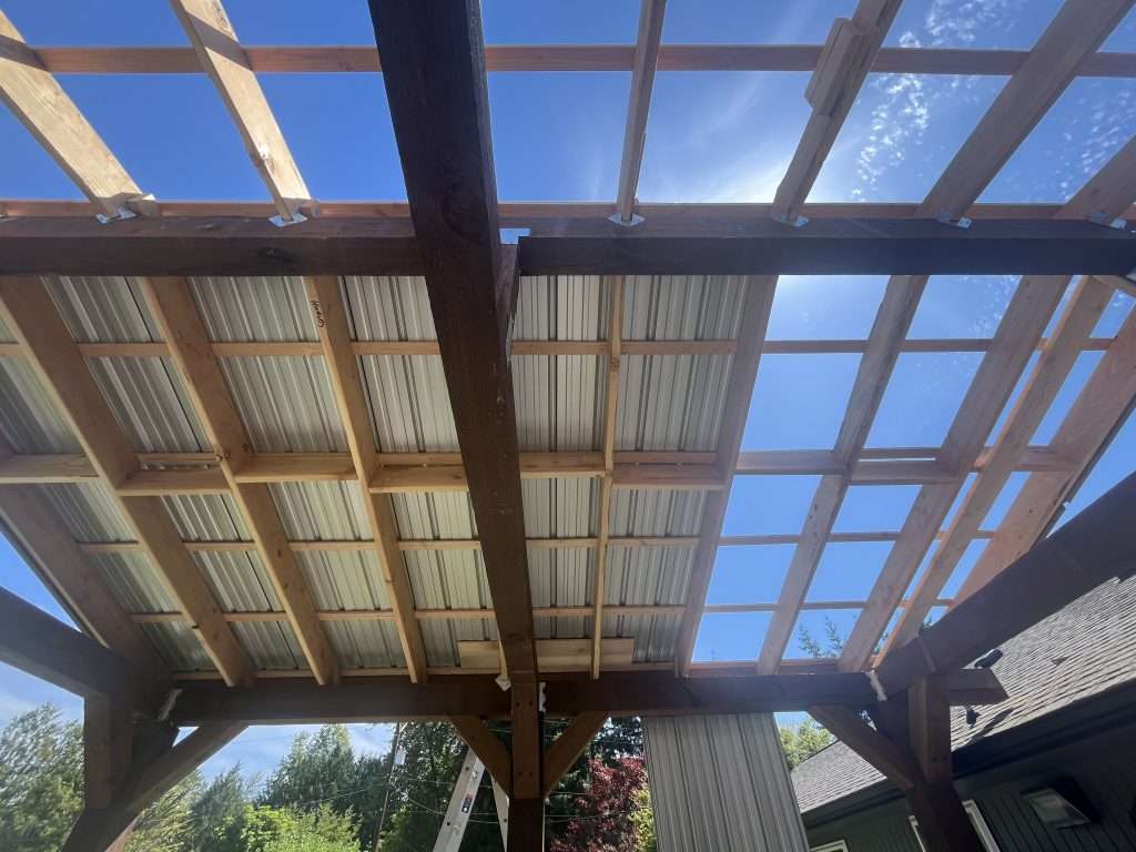 A view of the roof framing and partial metal roof of a custom patio cover.