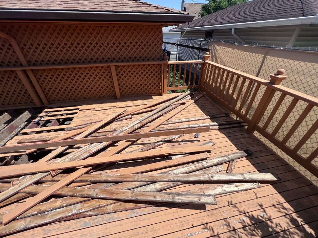 Wood planks lay on top of a deck as it is being torn out.