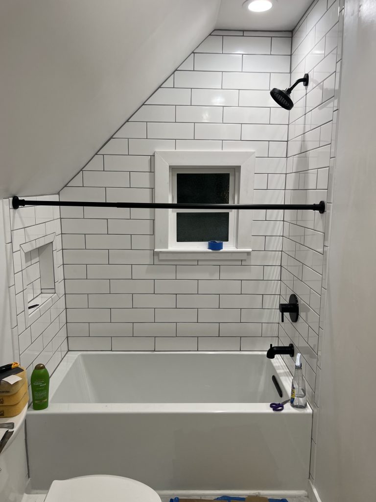 The final small bathroom remodel feaures a new tub with subway tile and built-in storage.