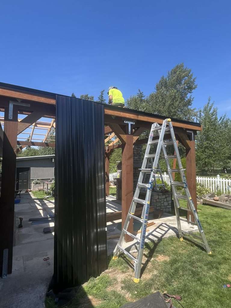 A contractor installs metal panes to the top of a patio cover.