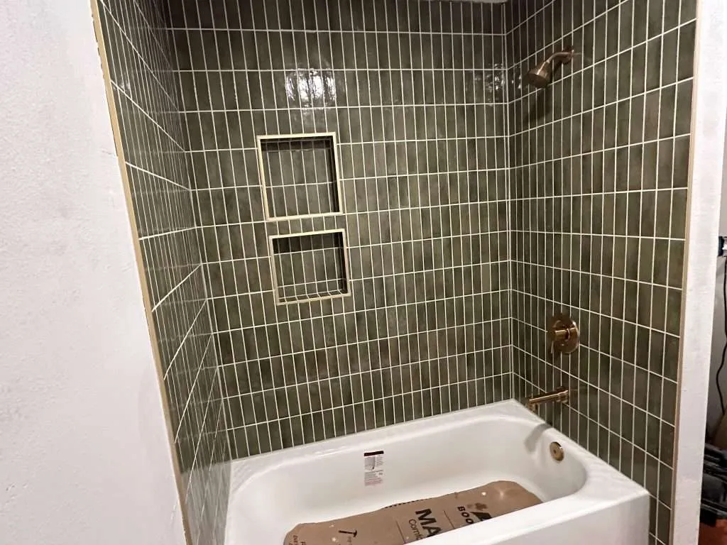 tiled bathtub shower with shelving and modern fixtures